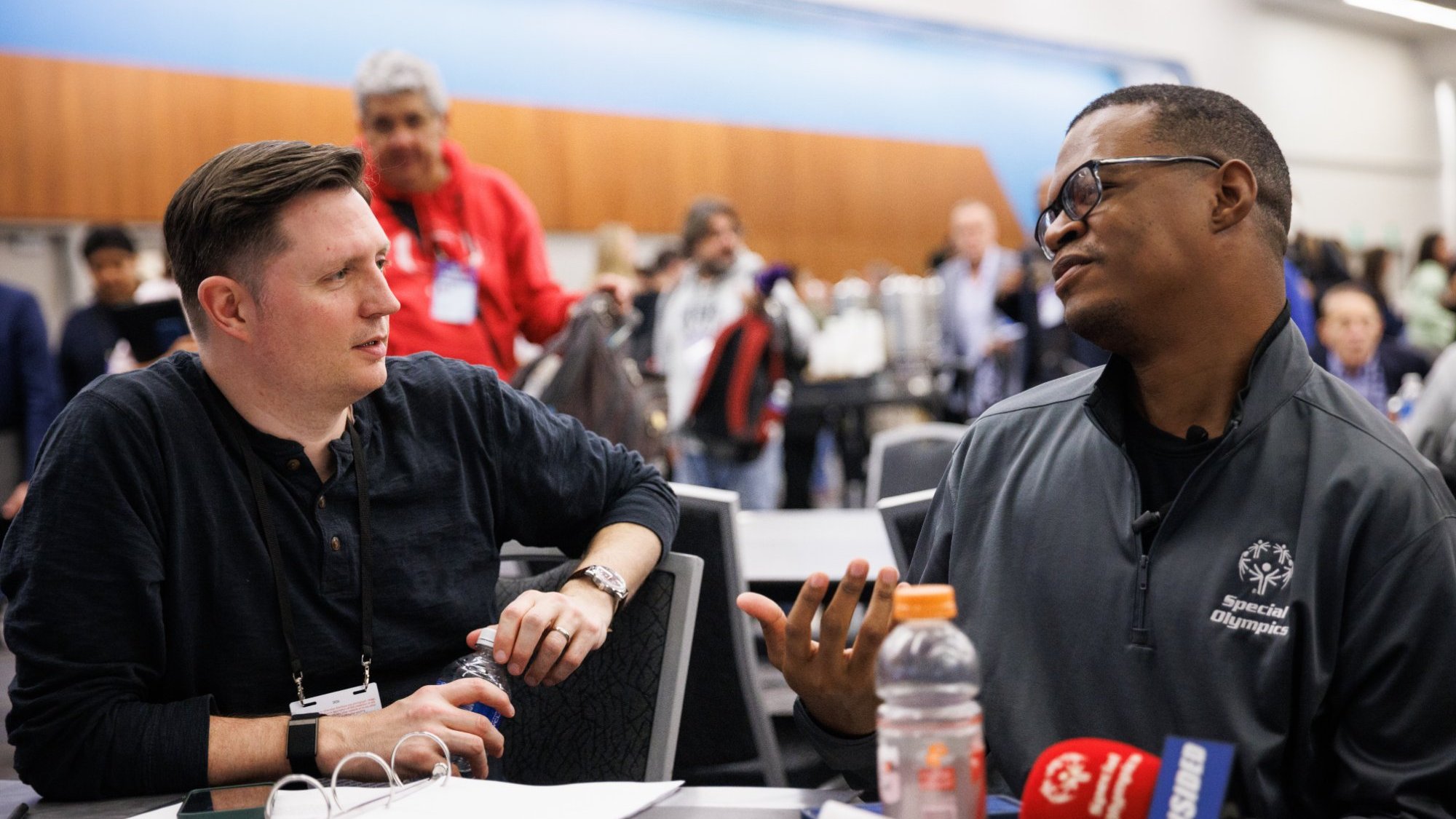 Malcom Harris-Gowdie at Super Bowl Media Week, wearing a Special Olympics jacket beside his FanSided microphone